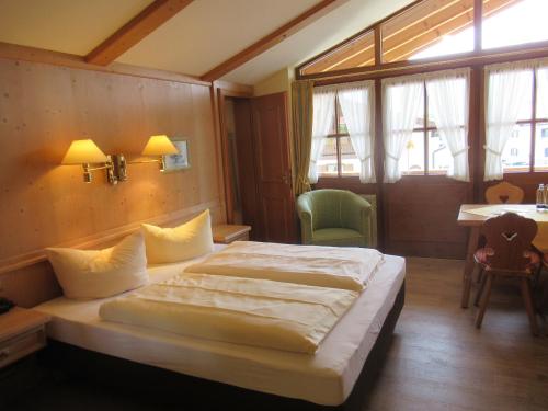 a bedroom with a bed and a table and windows at Sonnhof's Ferienresidenz in Reit im Winkl
