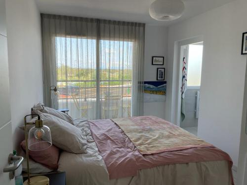 une chambre avec un lit et une grande fenêtre dans l'établissement Horizon Golf - Luxueux Appart vue piscine et golf - Wifi - Parking, à Saint-Cyprien