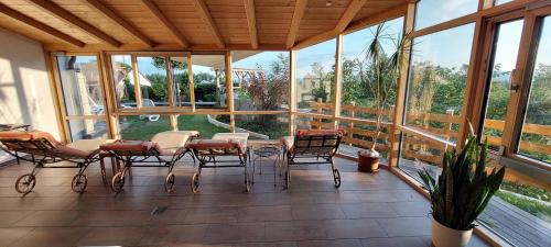 une terrasse couverte avec des chaises, des tables et une plante en pot dans l'établissement Panoramahotel Grobauer, à Spiegelau