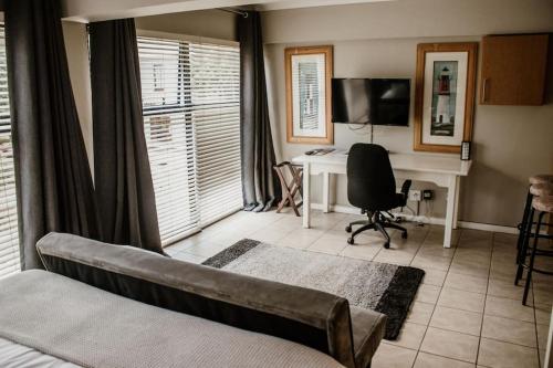 salon z kanapą i biurkiem z komputerem w obiekcie Concord Apartment w mieście Stellenbosch