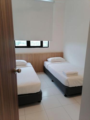 two beds in a small room with a window at CityViu at Imperio Professional Suites in Alor Setar