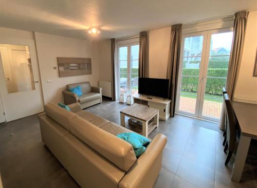 a living room with a couch and a tv at Triton suite Duinhof - Stijn Albrechtsstraat 1-6 in Cadzand