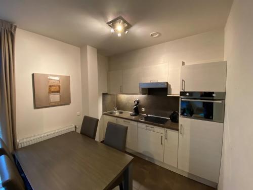 a kitchen with white cabinets and a table with chairs at Triton suite Duinhof - Stijn Albrechtsstraat 1-6 in Cadzand
