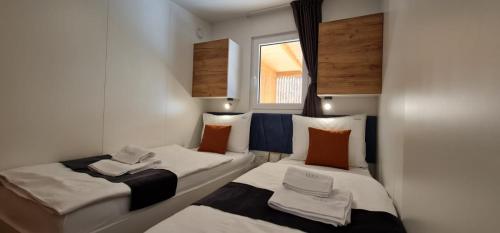 two beds in a small room with a window at Eliška Holiday Home in Biograd na Moru