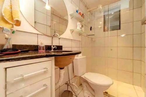 y baño con lavabo, aseo y espejo. en Apartamento aconchegante, en Natal