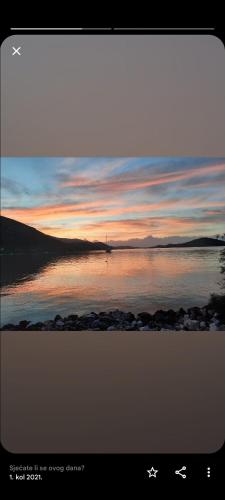 a sunset over a body of water with rocks at Cozy apartman in Luka