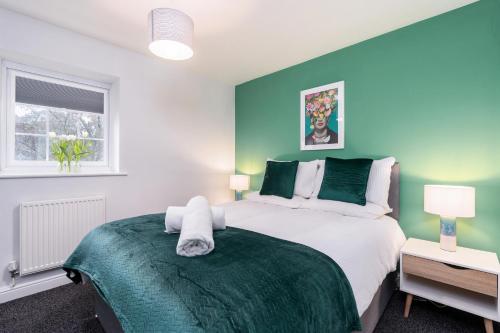 Un dormitorio con una cama con una pared de acento verde en Very Close to Manchester Airport and Wythenshawe Hospital - Tailored for Monthly and Long Term Stays, en Sale