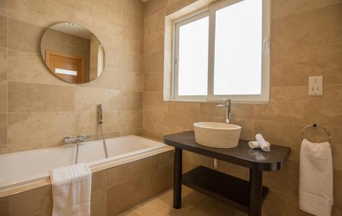 La salle de bains est pourvue d'un lavabo, d'une baignoire et d'un miroir. dans l'établissement VBH PENTHOUSE SPINOLA ST. JULIAN'S, à San Ġiljan