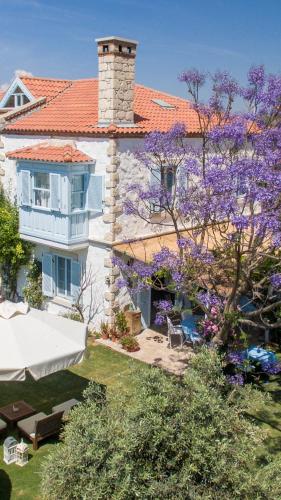 a house with a purple flowering tree in front of it at Deniz Kabugu Hotel in Alacati
