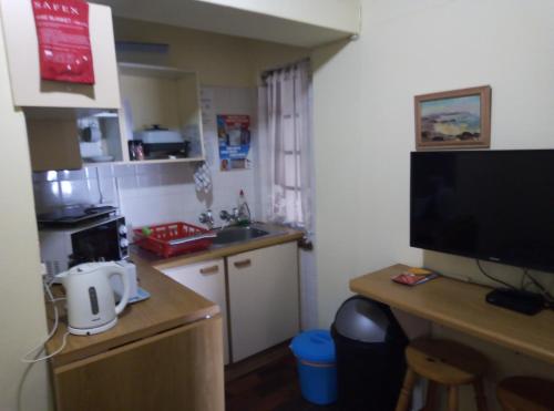 a small kitchen with a sink and a television at Far Niente Beachfront Guesthouse in Wilderness