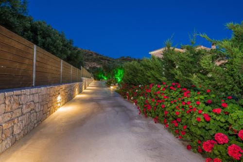 einen Weg mit Blumen und einer Mauer in der Unterkunft Romanza Luxury Villa in Kalamaki