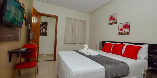 a bedroom with a bed with red pillows and a tv at Hotel Diamante Negro in Salvador