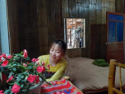 a young girl sitting on a bed next to a table at Thao Ly Homestay Mai Chau in Hòa Bình