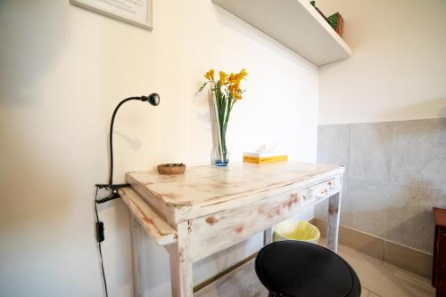 a desk with a vase of flowers and a lamp at B&B LELLA in Piove di Sacco