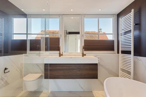 uma casa de banho com uma banheira, um WC e janelas em Villa Vermeer em Callantsoog