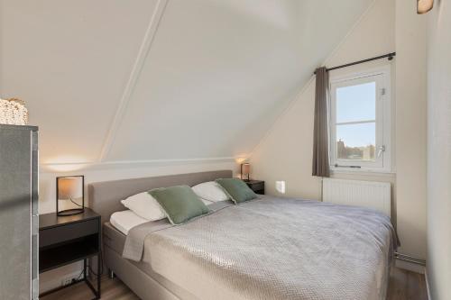 biała sypialnia z łóżkiem i oknem w obiekcie Villa Vermeer w mieście Callantsoog