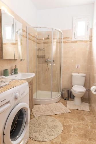 a bathroom with a shower toilet and a washing machine at Stegna Holiday in Archangelos