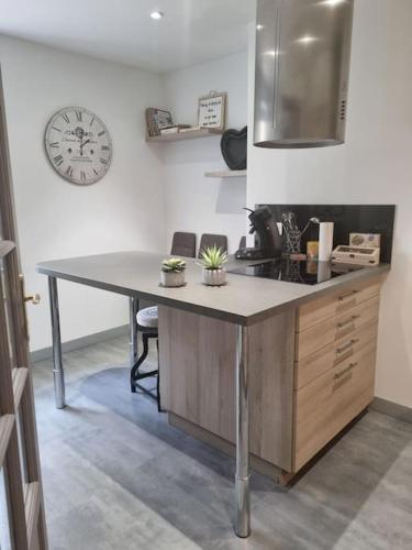 une cuisine avec une table et une horloge au mur dans l'établissement L'Ourse, Epinal,très bel appartement quartier Port, à Épinal