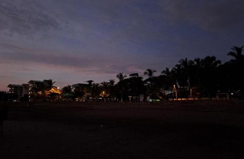 a beach at night with palm trees and buildings at Tropical Garden Hotel in Jacó