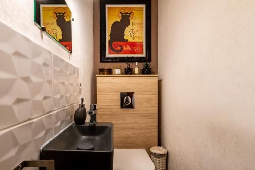 ein Bad mit einem schwarzen Waschbecken und einem WC in der Unterkunft Charmante Maison Climatisée avec son Jardin à 5 minutes de DIJON in Saint-Apollinaire