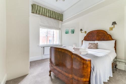 een slaapkamer met een groot bed met een houten hoofdeinde bij St James Westminster Apartment in Londen