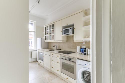 cocina con armarios blancos, lavadora y secadora en St James Westminster Apartment, en Londres