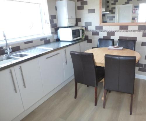 a kitchen with a table and chairs and a microwave at Daisychain Holidays in Bridlington