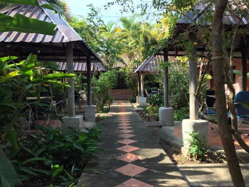 a walkway through a garden with a building at Captain Chim's Guest House in Kep
