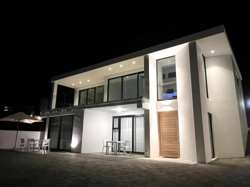 una gran casa blanca por la noche con mesas y sillas en Flip Flops Villa, en Yzerfontein