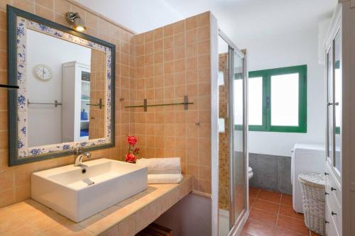 y baño con lavabo blanco y espejo. en Hermosa Casa vacacional, muy cerca a la playa., en Guatiza