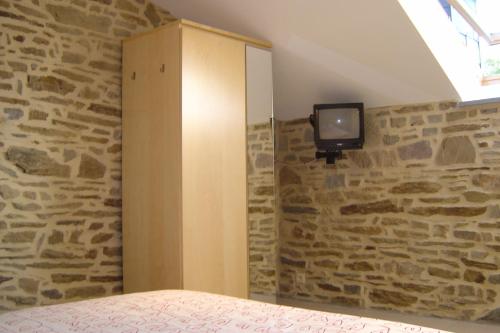 a bedroom with a tv on a stone wall at Holiday home Gîte rural Côté Fagnes in Jalhay