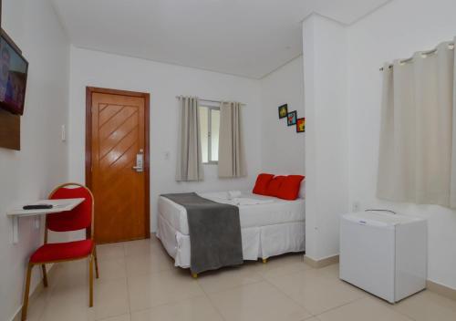 a bedroom with a bed and a table and a red chair at Hotel Diamante Negro in Salvador