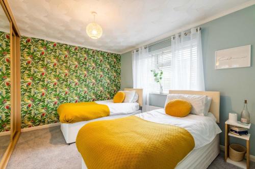 two beds in a room with yellow and green wallpaper at Host & Stay - Gorse Cottage in Mundesley