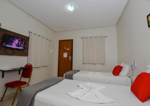 a room with two beds and a chair and a tv at Hotel Diamante Negro in Salvador