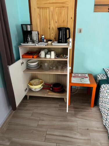 a kitchen with a cupboard with dishes and a table at L'Escale du Mouillage in Saint-Pierre