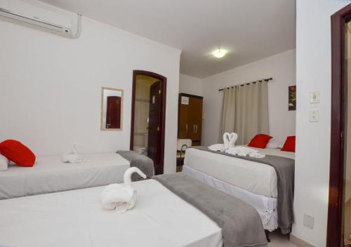 a hotel room with three beds with swans on them at Hotel Diamante Negro in Salvador