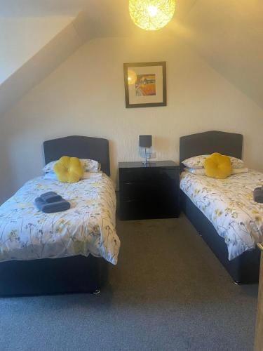 a bedroom with two beds with yellow pillows at Cosy detached house in central location in Oban
