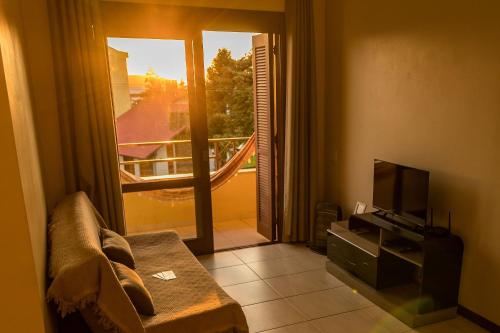 sala de estar con sofá, TV y balcón en Condomínio Familiar - Aptos Novos e Completos en Nova Petrópolis