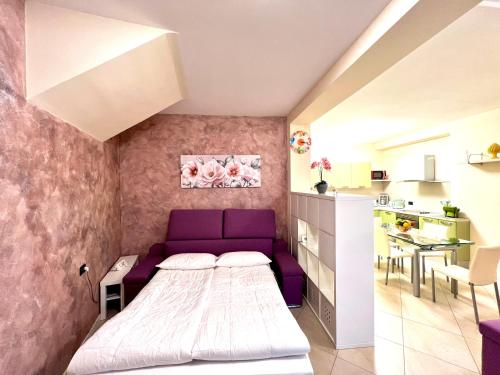 a small bedroom with a purple bed and a kitchen at Limone DownTown in Limone sul Garda