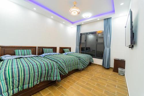 two beds in a room with a purple ceiling at COMFORT CHALET & APARTMENTS in Al Ḩadd