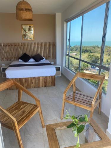 1 dormitorio con cama, sillas y ventana grande en Hotel Bahia Rada, en Moñitos