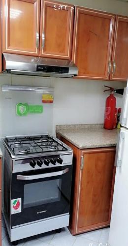a kitchen with a black stove and wooden cabinets at Lemas 1001 in Ajman