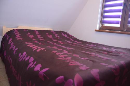 a bed with a purple blanket with pink flowers on it at Domek Maja in Wołkowyja
