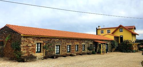 a large brick building with a yellow building at Quinta do Chao D'Ordem in Vila Nova de Foz Coa