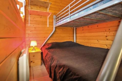 une chambre avec un lit dans une cabane en bois dans l'établissement Le Clos Chantéric accueille jusquà 5 personnes, à Thueyts