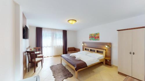 a bedroom with a bed and a desk and a chair at Garni Hotel Fatra in Terchová