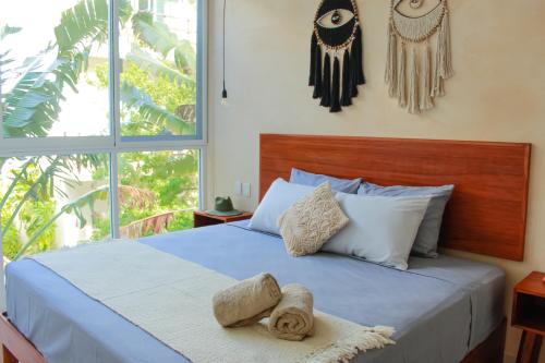 a bedroom with a blue bed with a large window at Gama 09 Apartments in Tulum
