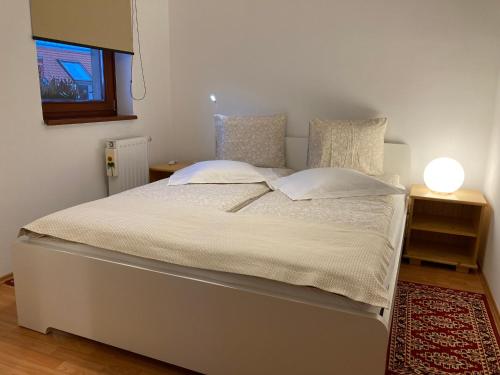 sypialnia z białym łóżkiem i lampą na dywanie w obiekcie Germar Apartman w mieście Pecz