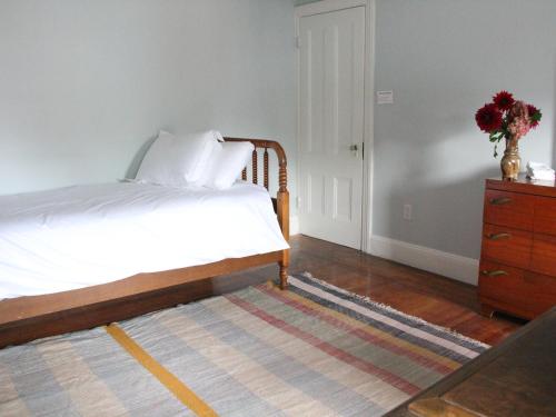 a bedroom with a bed and a dresser with a vase of flowers at The Wedding Cake House in Providence