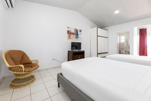 a white bedroom with a bed and a chair at Bella Surf Inn in Isabela